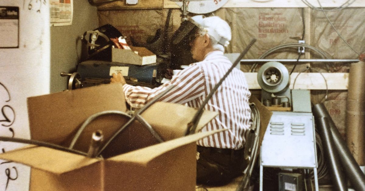 Archival workshop photograph showing hose equipment and a person at a workbench
